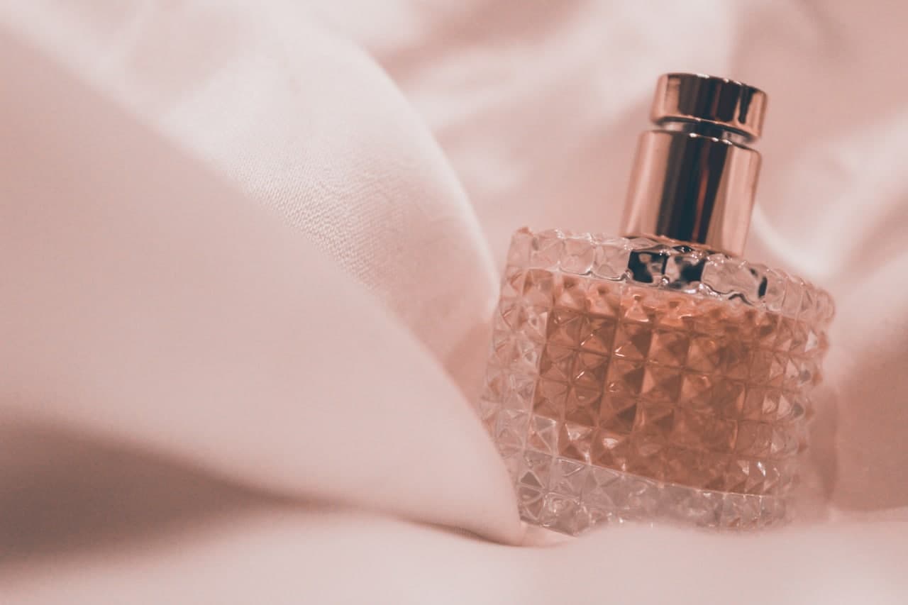 a bottle of perfume on the pink fabric