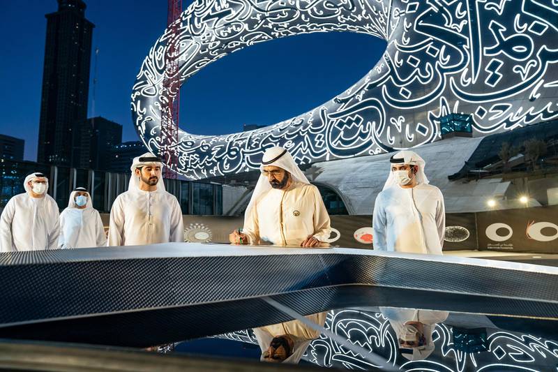 Accompanied by Sheikh Hamdan bin Mohammed and Sheikh Maktoum bin Mohammed, Sheikh Mohammed bin Rashid is signing the papers at the installation of the final piece of facade at the Museum of the Future