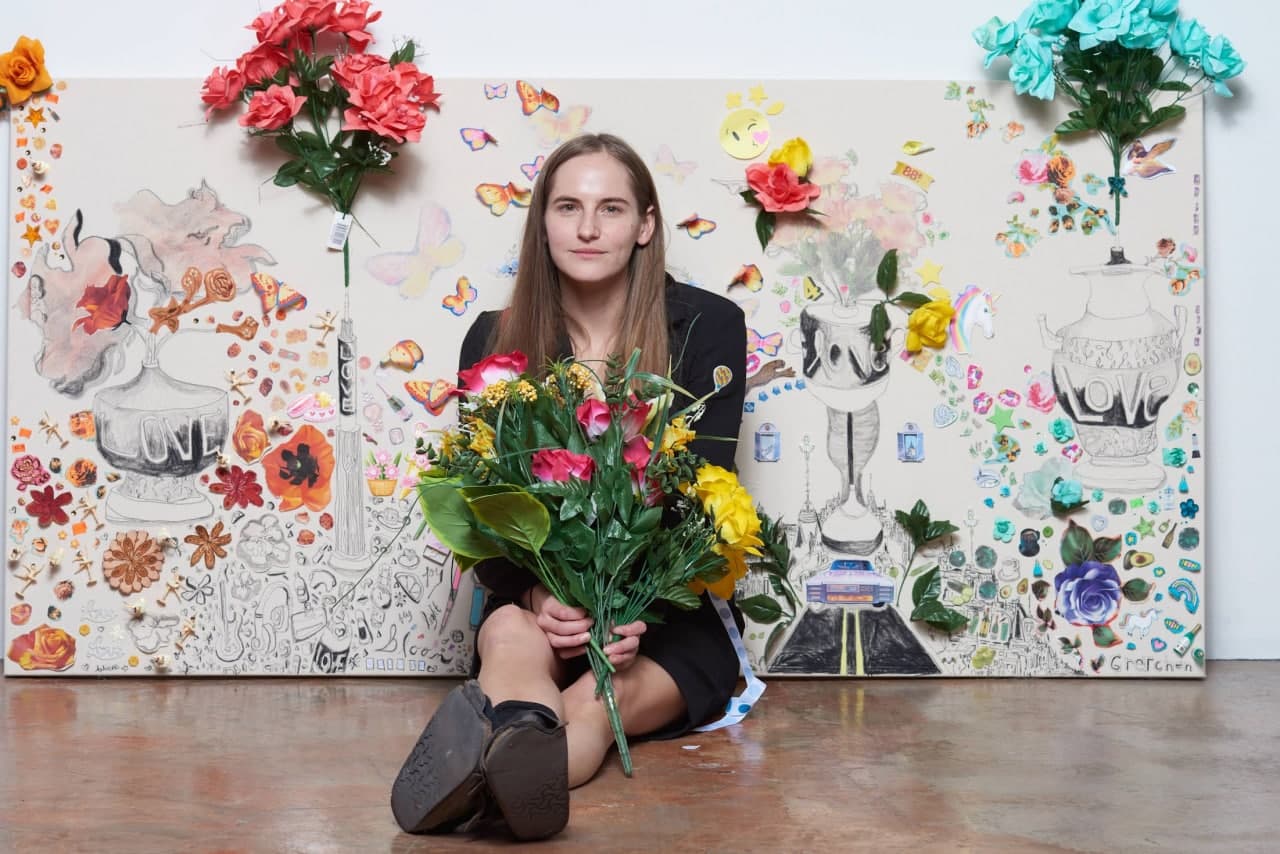 Gretchen Andrew sitting on the floor with a bouquet of flowers in hands